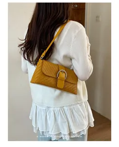 Detailed view of the stylish yellow woven underarm bag featuring a chic silver buckle.