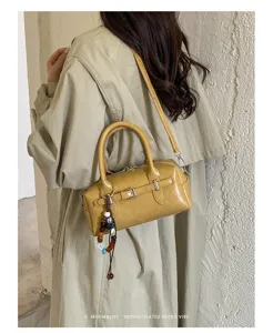 Yellow patent leather Boston handbag with beaded charm, stylish retro shoulder bag detail.