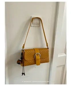 Yellow woven shoulder bag detail, stylish baguette handbag with metal buckle and charm.