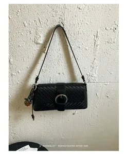Detailed view of a chic black woven shoulder bag featuring a stylish metallic buckle and charm.