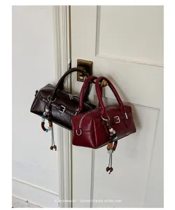 Detail view of retro Boston handbag, PU leather shoulder bag with beaded charm detail.