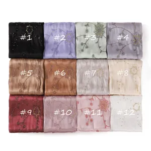 Detailed close up of lightweight island silk satin scarves with spiderweb sequin embroidery.