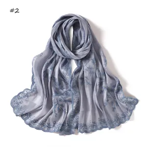 Detailed close-up view of elegant grey long scarf with blue embroidery and delicate sequins.