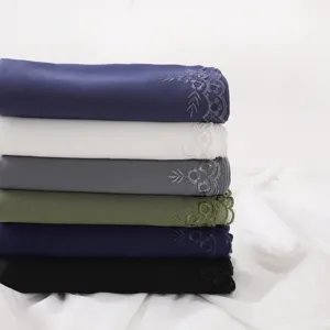 Vista dettagliata della pila di hijab in chiffon ricamati con delicato bordo floreale.