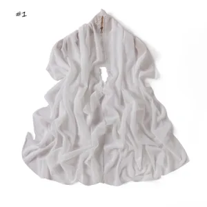 Dettaglio di sciarpa in chiffon bianco con ricami floreali e bordi delicati e morbidi.