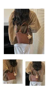 Vue détaillée du sac seau tissé élégant mettant en valeur la texture et la breloque florale.