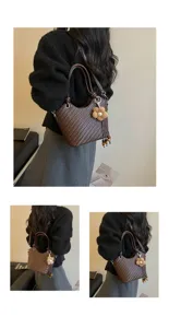 Vue détaillée du sac seau tressé marron foncé avec charmant pendentif de fleur et poignée nouée.