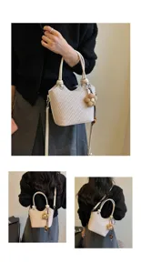 Vue detaillee du sac seau tisse elegant avec pendentif fleur, porte par le modele.