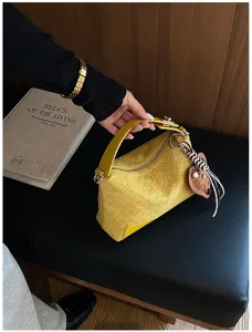 Vista dettagliata della borsa in pelle intrecciata gialla con chiusura lampo e ciondolo.