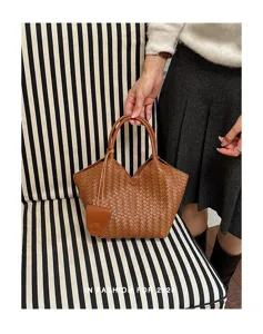 Detailed shot of stylish brown woven leather tote bag with unique V-shape design and charm.