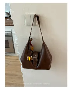 Λεπτομερής λήψη της κομψής ρετρό καφέ slouchy hobo τσάντας κρεμασμένης στον τοίχο.