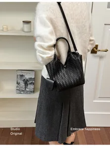 Detailed view of black woven leather shoulder bag with top handle and stylish mini pouch.