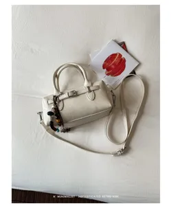 Close-up detail of a white Boston pillow bag with beaded strap charm and minimalist style.