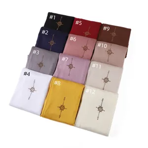 Detailed view of mercerized cotton hijab with golden rhinestone cross and colors.