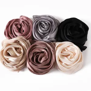 Detail view of soft satin silk scarves rolled into rose shapes, versatile solid colors for women.