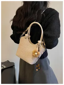 Vue détaillée d'un sac seau élégant en cuir tressé beige avec pendentif de fleurs.