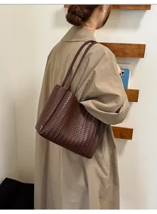 Brown woven leather tote bag shoulder detail, vintage style daily commuting accessory.