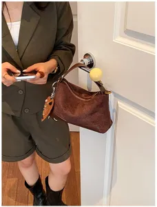 Vista dettagliata della borsa a mano intrecciata marrone rétro con zip e ciondolo.
