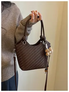 Gros plan sur le sac seau tressé marron élégant doté d'un charmant pendentif floral.