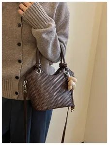 Vue détaillée du sac seau tressé marron avec charm fleur et bandoulière élégante.
