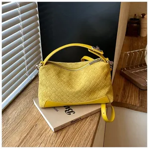 Primo piano di borsa a mano intrecciata gialla con dettagli di texture e finiture.