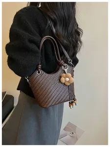 Vue détaillée du sac seau tressé marron foncé élégant avec charmant pendentif fleur et perles.