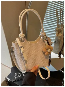 Vue détaillée d'un sac seau tissé élégant avec poignée chic et charmant accessoire de fleur.