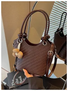 Détail exquis du sac seau tissé présentant une texture en cuir et de jolies poignées.