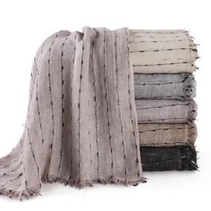 Vue détaillée de foulards en coton et lin empilés avec fils d'argent métalliques et franges.