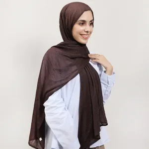Close-up detail of the brown textured hijab scarf fabric, showing soft pleated polyester.