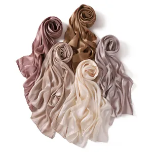 Detailed close-up view of elegant satin silk scarves rolled up in various neutral tones.