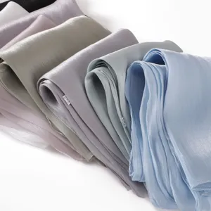 Detail view of colorful crinkled satin scarves, soft draping fabric texture closeup.