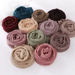 Detailed shot of crinkled polyester hijabs in various solid colors nicely rolled.