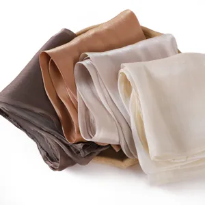 Close-up of luxury solid color shiny satin long scarves in neutral colors neatly folded.