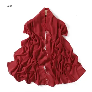 Dettaglio sciarpa chiffon rosso con ricamo floreale, elegante coprispalle da donna.