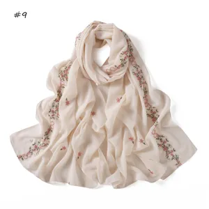 Delicate pink floral and ribbon embroidery detail on lightweight chiffon scarf fabric surface.