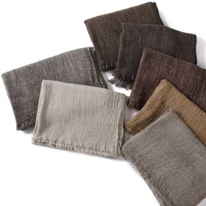 Detailed view of solid color crinkle cotton long scarves featuring delicate frayed fringe edges.
