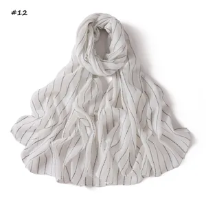 Detail view of lightweight white scarf featuring thin vertical stripes and colorful sequins.