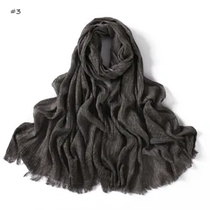 Detailed view of the dark grey crinkled textured fringe scarf showing fine pleated fabric.