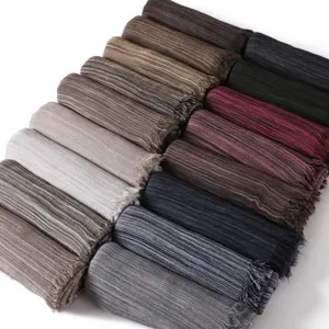 Detailed view of multiple rolled striped fringed scarves in various colors showing fine textures.