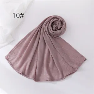 Detail view of a soft crinkled polyester scarf in dusty pink, elegant coiled fabric texture.