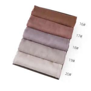 Detail view of rolled solid color modal linen scarves in assorted earthy tones, neatly displayed.