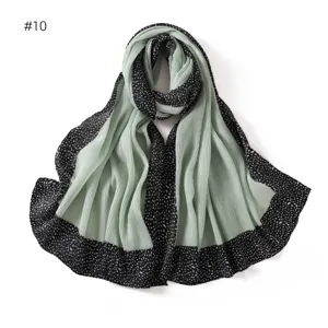Close-up detail of the pleated long scarf with black dotted border and sage green center.