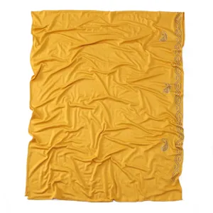 Detail view of yellow mercerized cotton scarf featuring rhinestone waves and paisley patterns.