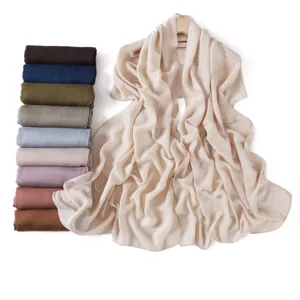 Close-up detail showing stacked colorful modal cotton linen scarves and a draped beige scarf.