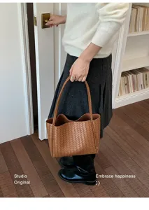 Detailed view of brown woven leather tote bag, showcasing premium craftsmanship and elegant style.