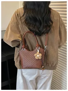 Sac seau tressé chic pour femme, élégant sac à bandoulière marron avec joli pendentif fleur.