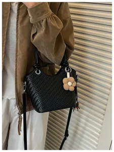 Vue détaillée d'un sac seau tressé, élégant sac à bandoulière noir avec charmant pendentif fleur.