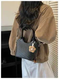 Détail du sac seau tissé noir pour femme avec charm fleur mignon et poignée chic élégante.