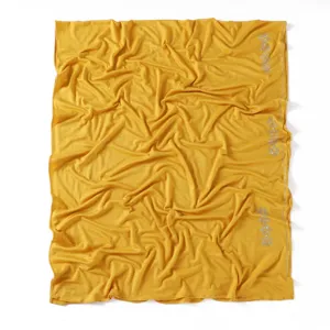 Close-up detail of yellow jersey scarf featuring rhinestone floral motifs and delicate trim.